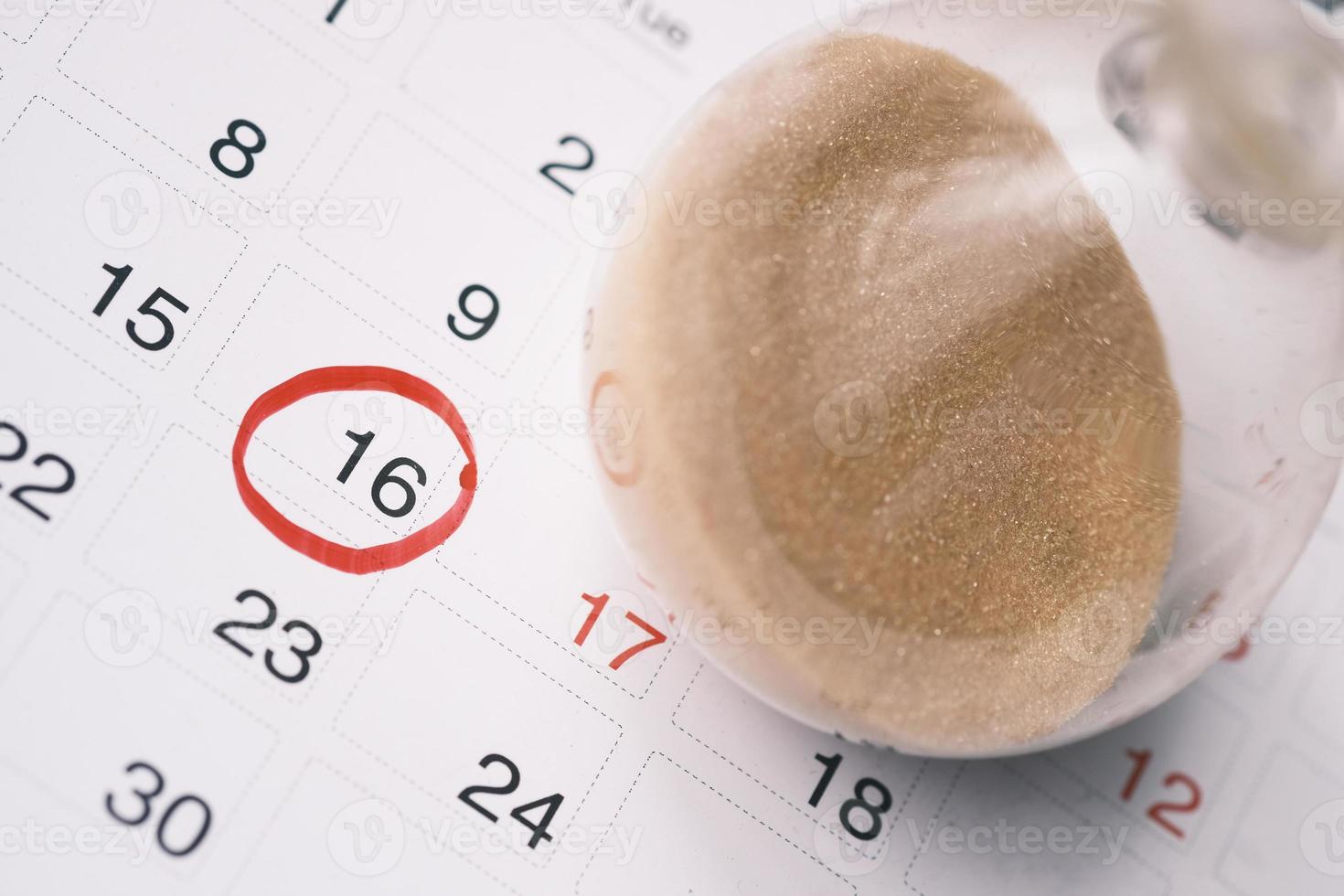 hourglass on a calendar, and flowing through the bulb of sandglass photo