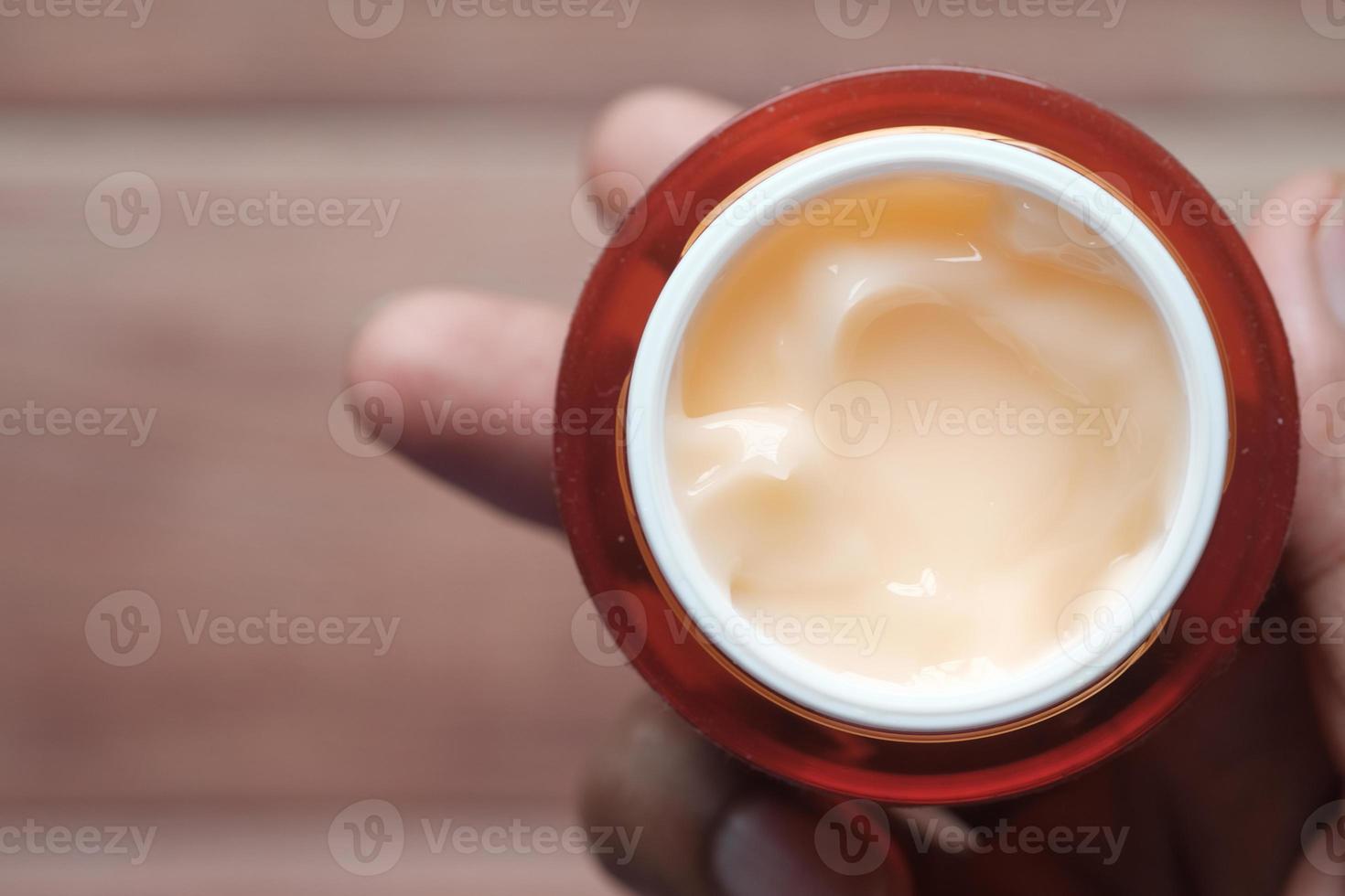 person hand holding a face cream container photo