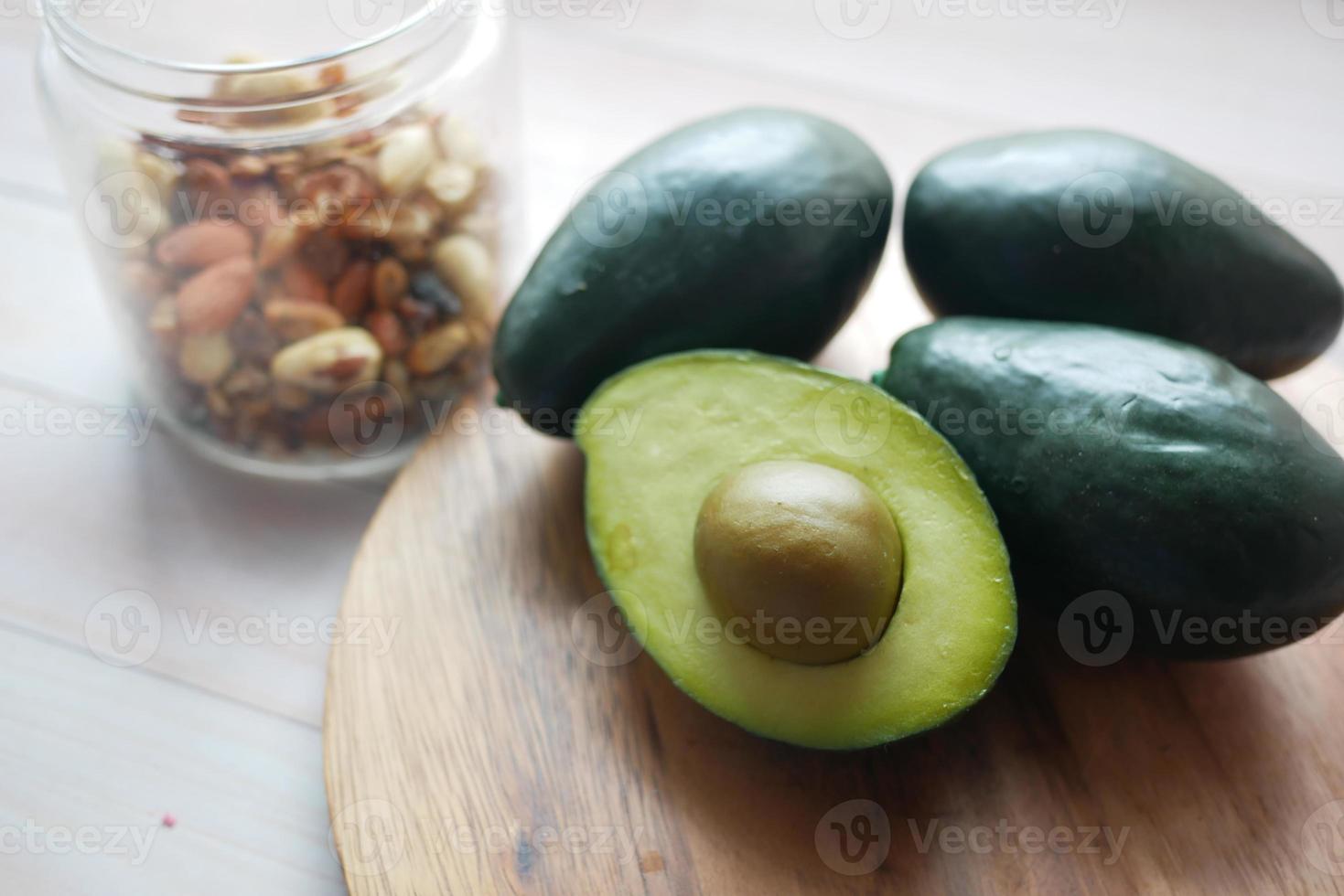 Cerca de una rodaja de aguacate y nueces mixtas sobre una tabla de cortar. foto