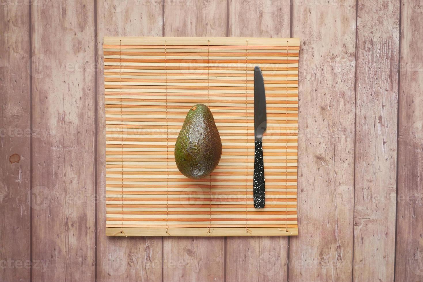 top view of slice of avocado and knife on wooden table photo