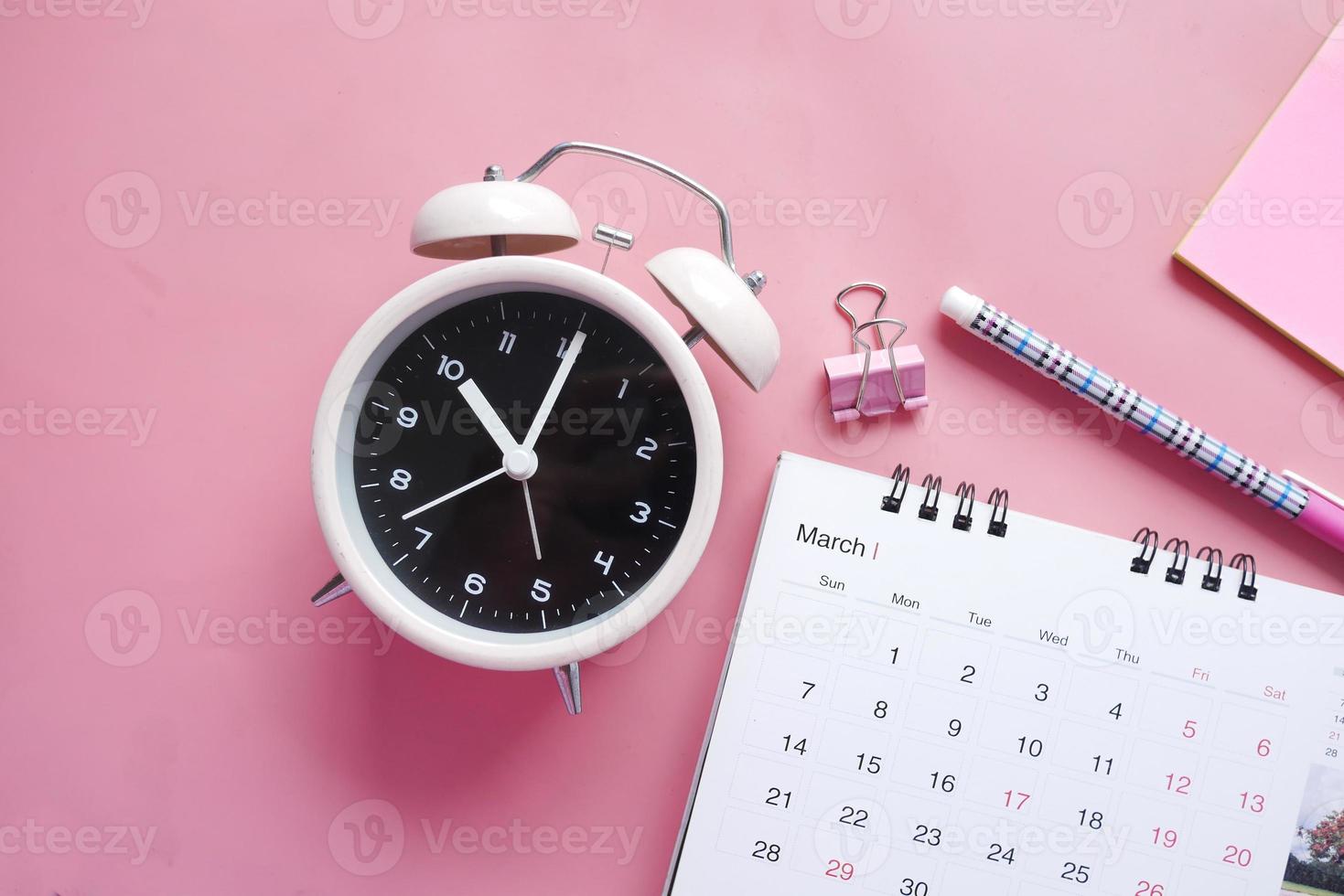 concepto de fecha límite con calendario y despertador en rosa foto