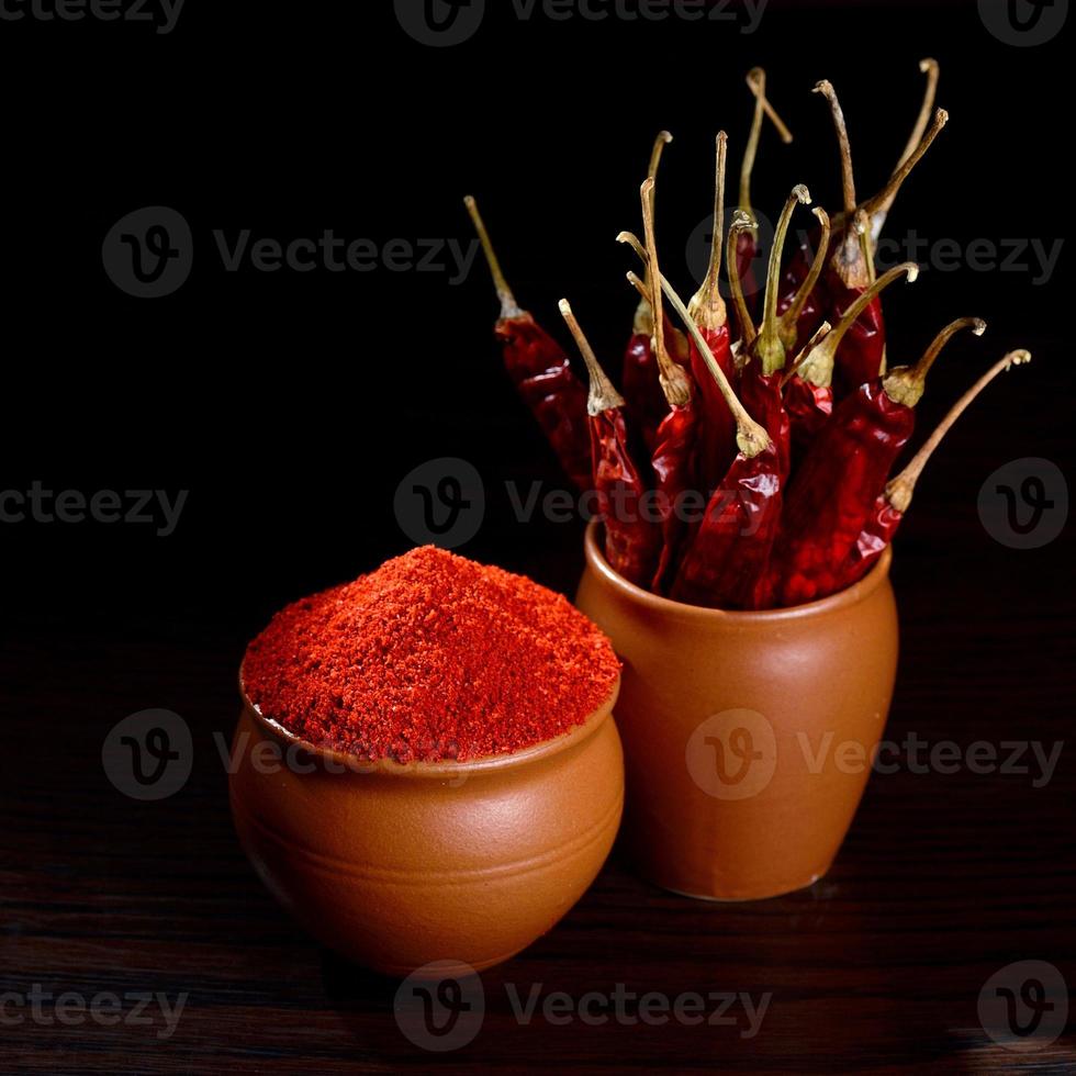 chilly powder with red chilly in clay pots, dried chillies on dark background photo