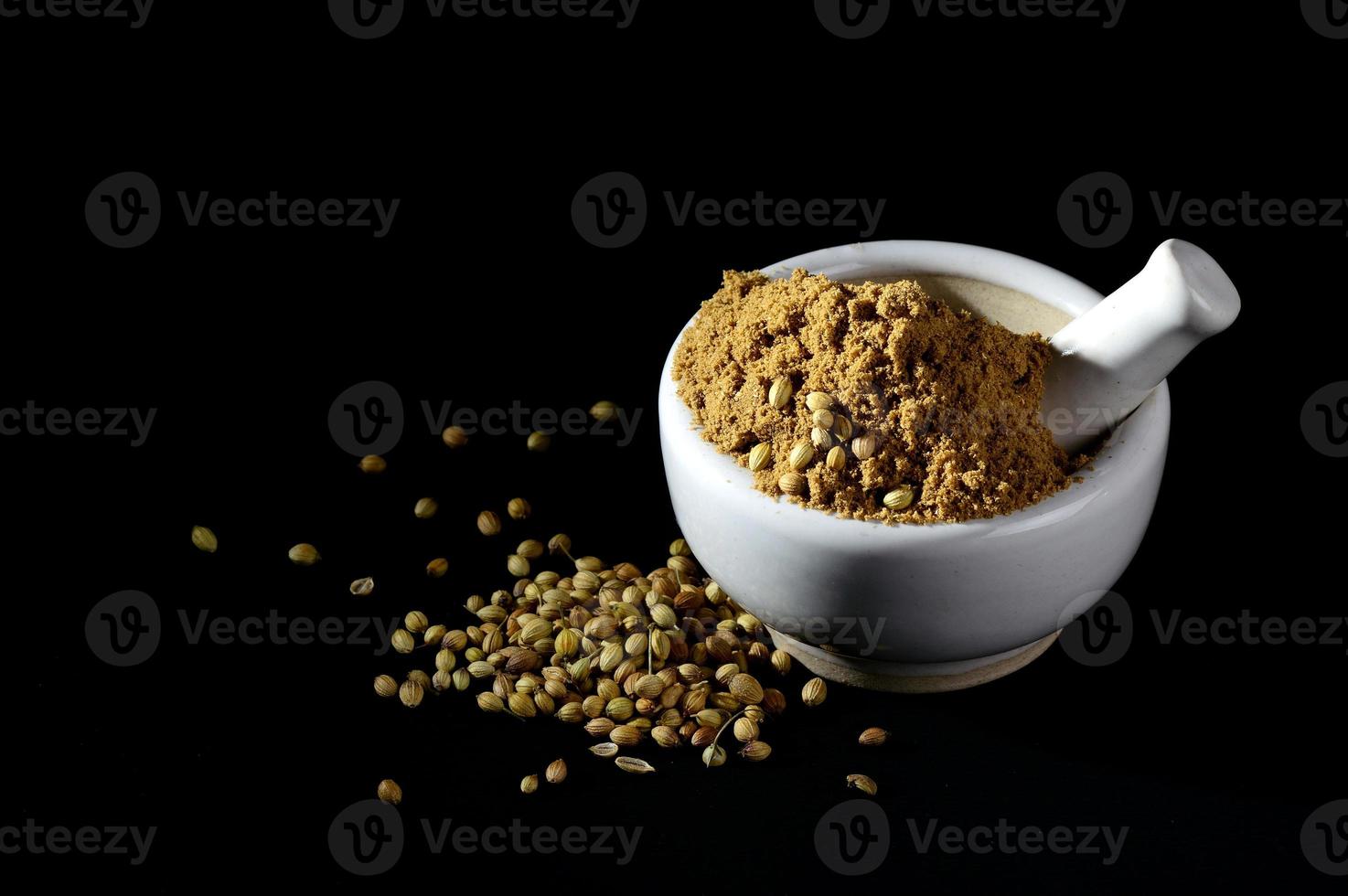 Coriander Powder and seeds with mortar and pestle on black background. photo