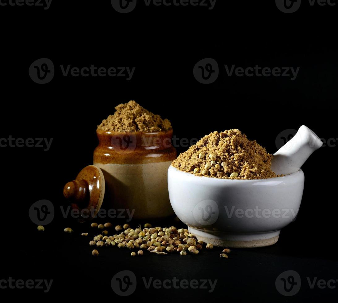 mortar and pestle with Coriander Powder and seeds on black background. photo