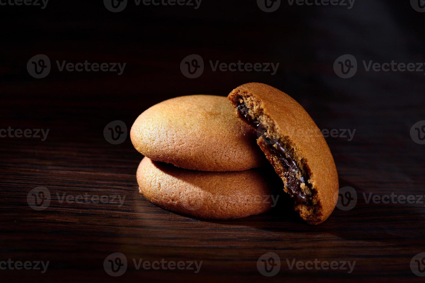 galletas rellenas de crema de chocolate. galletas de crema de chocolate. Galletas de chocolate marrón con relleno de crema sobre fondo negro. foto