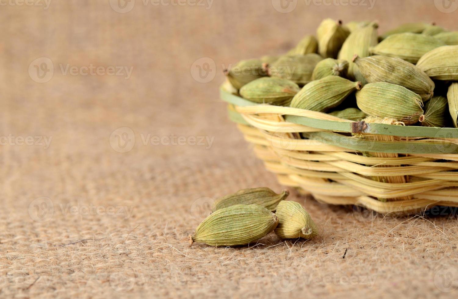 Vainas de cardamomo verde en canasta de bambú sobre tela de saco foto