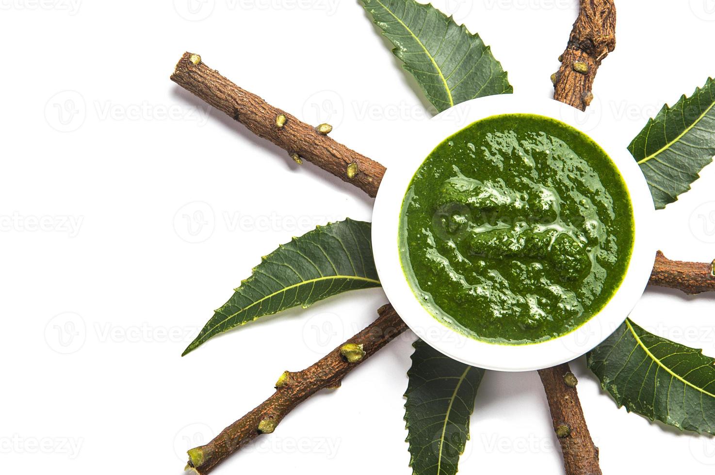 Medicinal Neem leaves with paste in bowl and twigs on white background photo