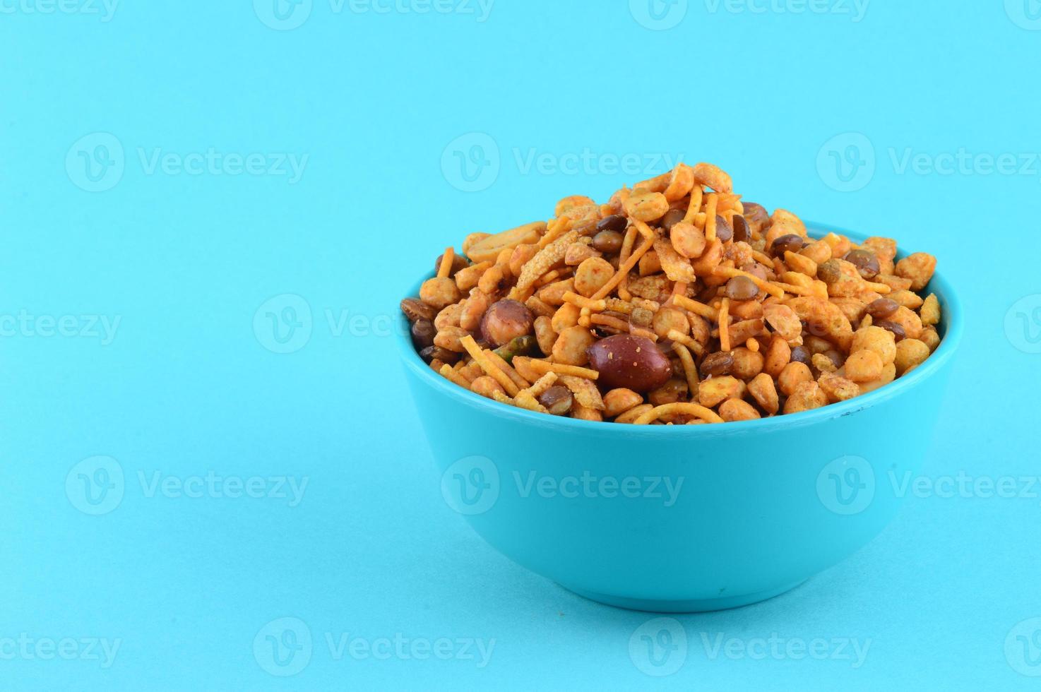 Indian Snacks Mixture roasted nuts with salt pepper masala, pulses, channa masala dal green peas in blue bowl in photo