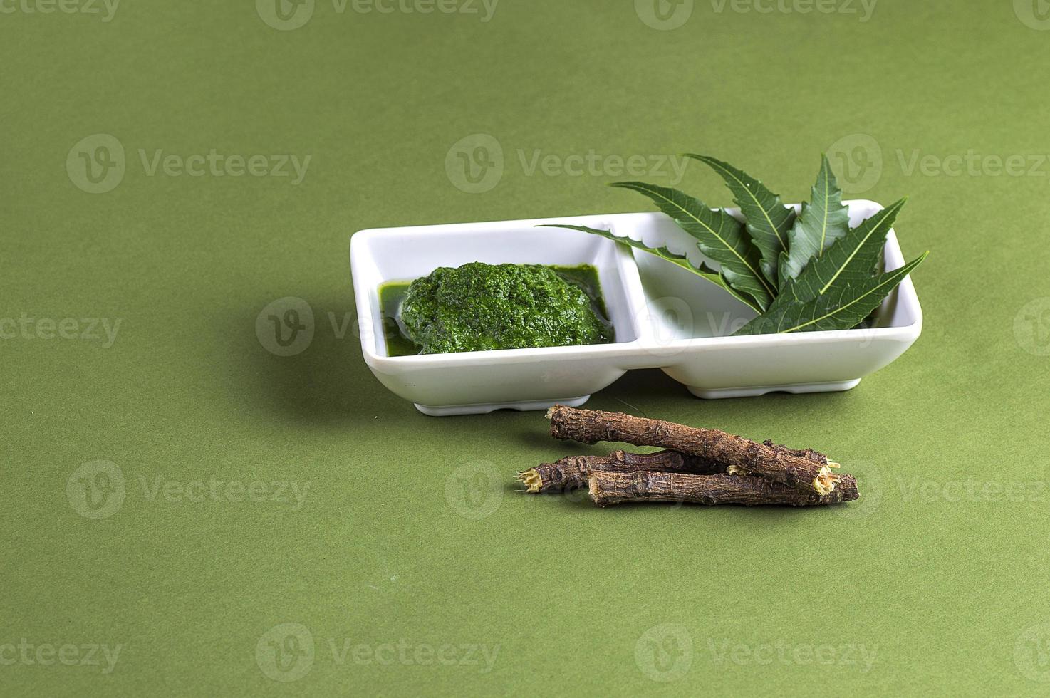 Pasta de hojas de neem medicinal y hojas con ramitas sobre fondo verde foto