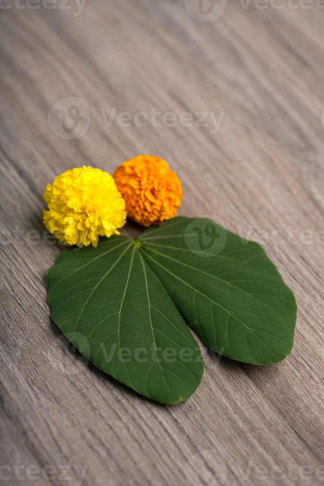 Indian Festival Dussehra, showing golden leaf Bauhinia racemosa and marigold flowers on a wooden background. photo