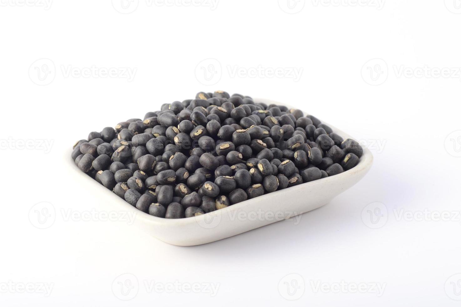 urad dal, gramo negro, vigna mungo en placa blanca sobre fondo blanco. foto