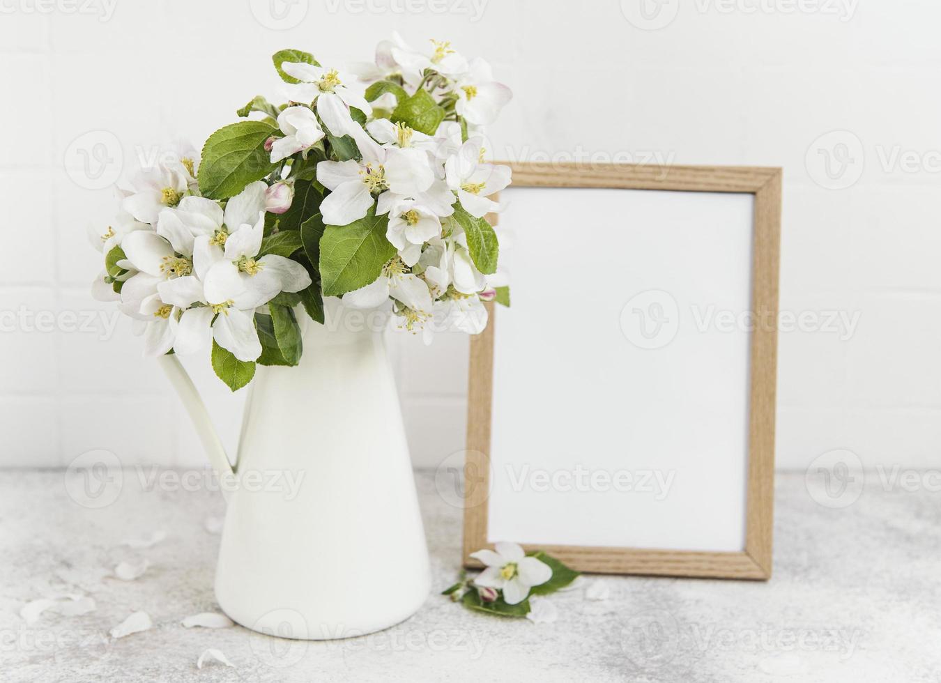 flor de manzana de primavera en un jarrón con un marco de fotos vacío