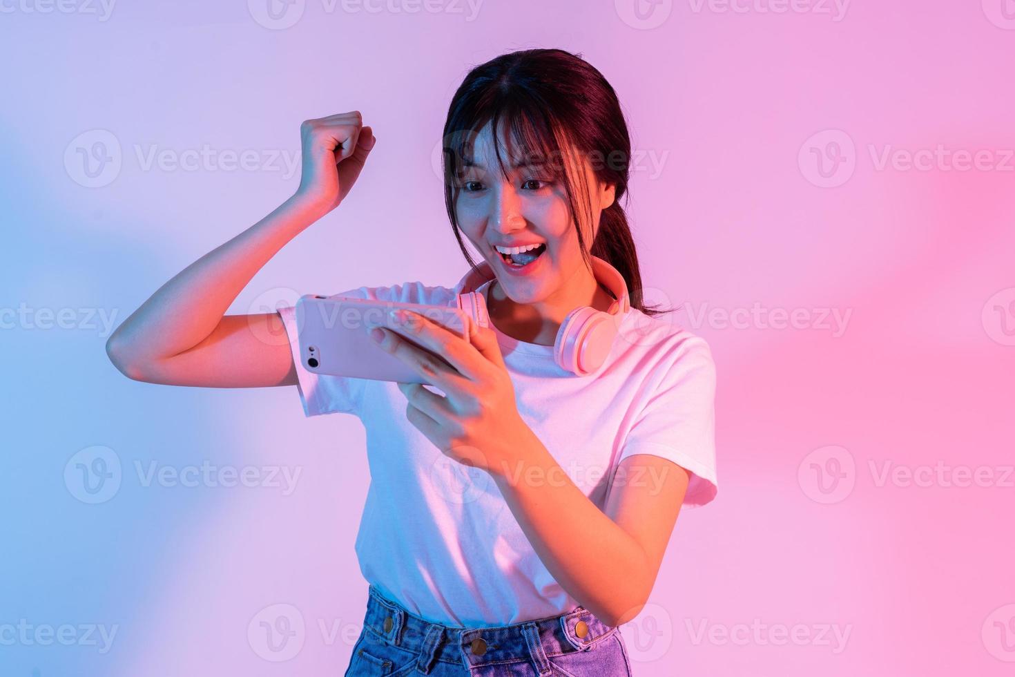 Young Asian girl playing game on phone with excitement photo