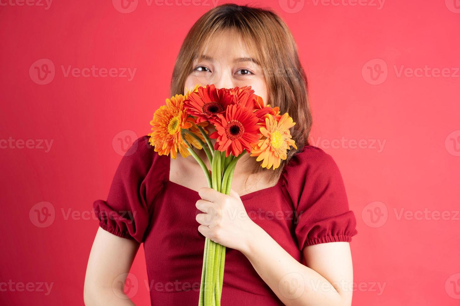 Young girl holding bouquet of gerberas with cheerful expression on background photo