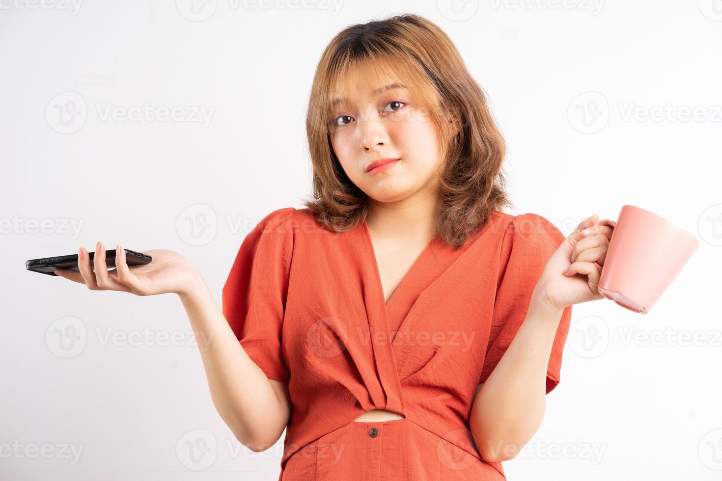 Mujer sosteniendo una taza de agua y teléfono con expresión de fondo foto