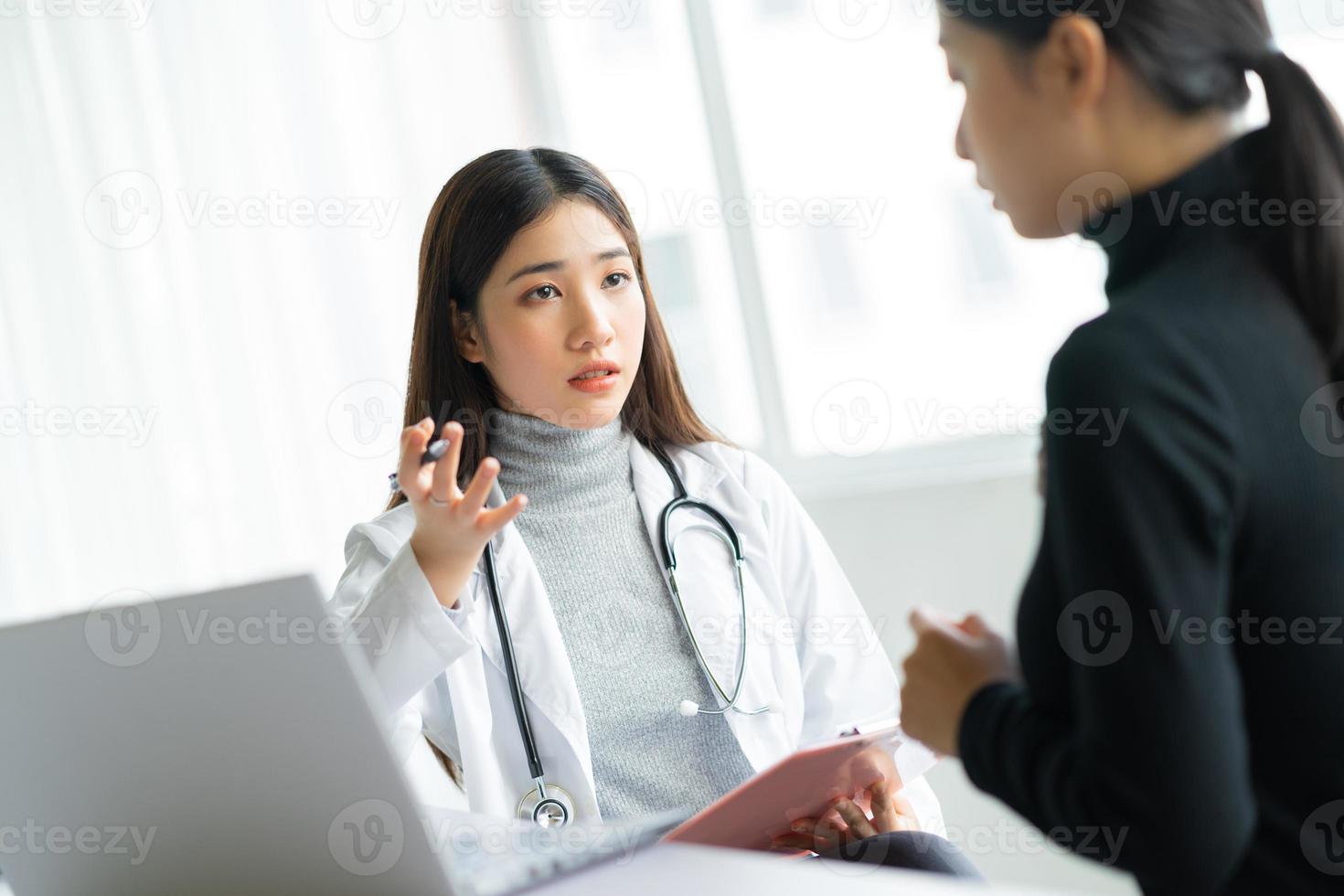 Doctora asiática está examinando a los pacientes en la clínica foto