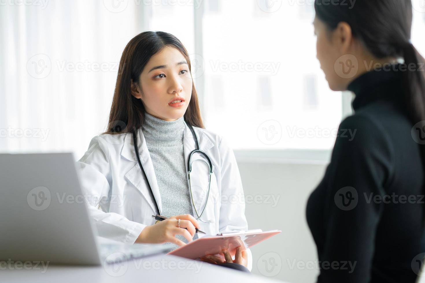 Doctora asiática está examinando a los pacientes en la clínica foto