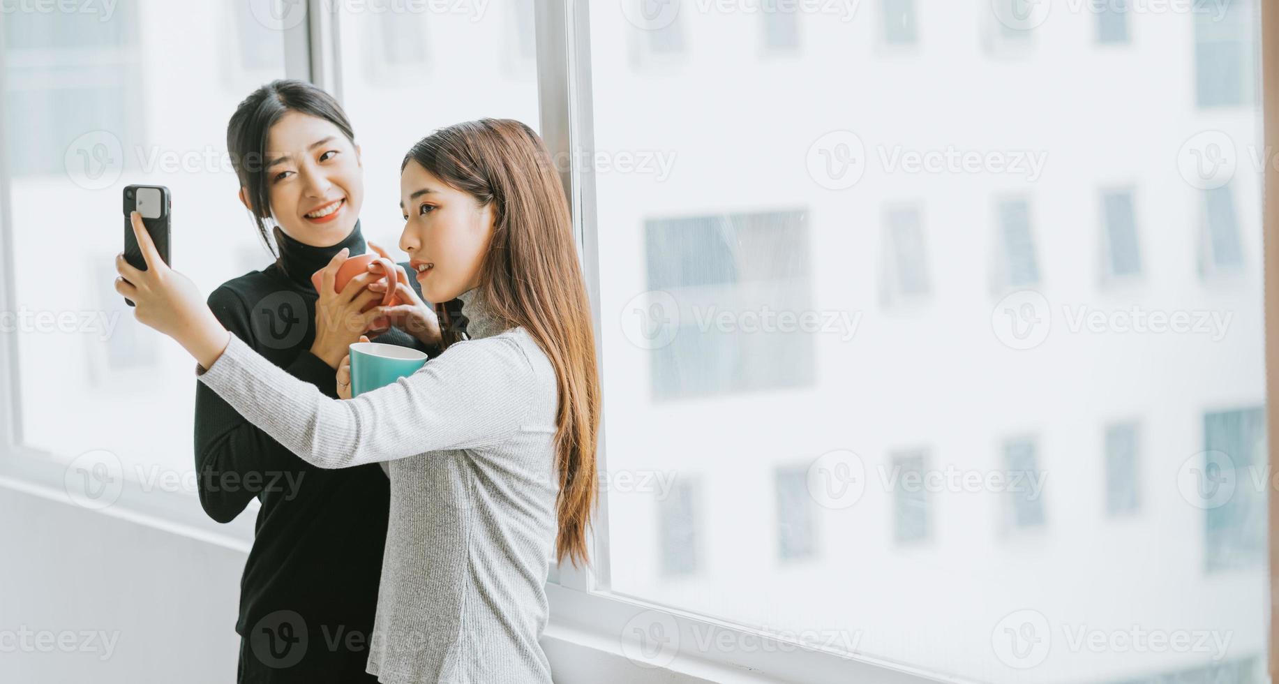 Two Asian business women were chatting by the window during recess photo