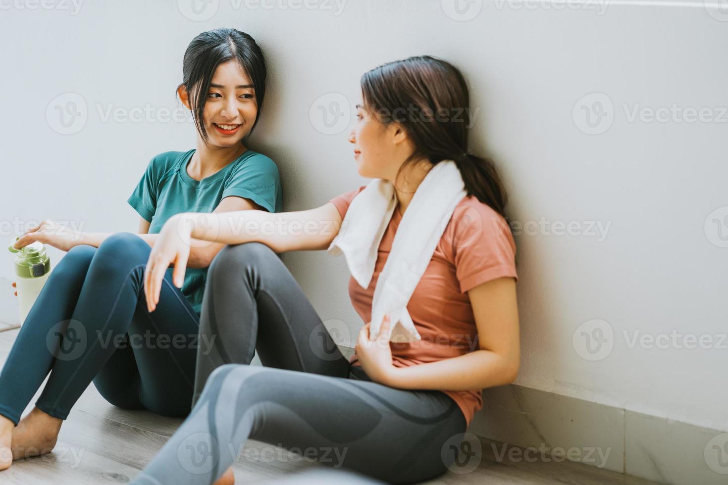 dos mujeres asiáticas tomando un descanso de la sesión de yoga foto