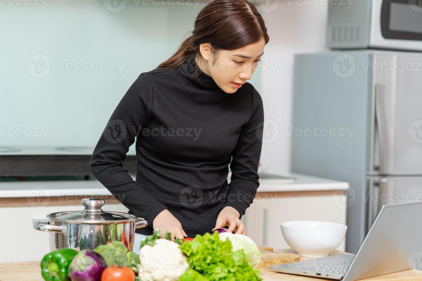 mujer está aprendiendo a cocinar sola en casa, curso de cocina en línea foto