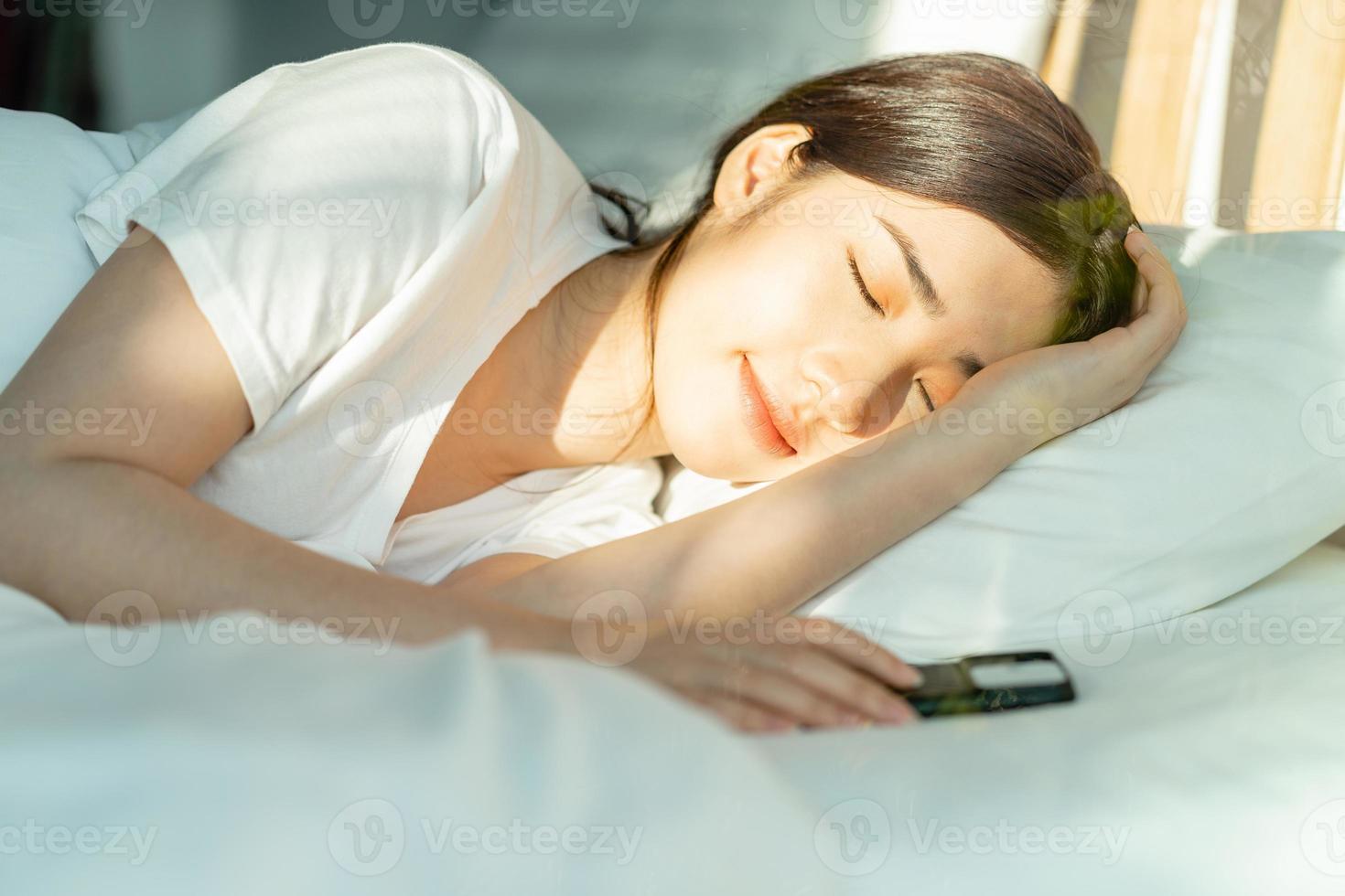 la hermosa mujer asiática dormía pasado el mediodía con su teléfono a su lado foto