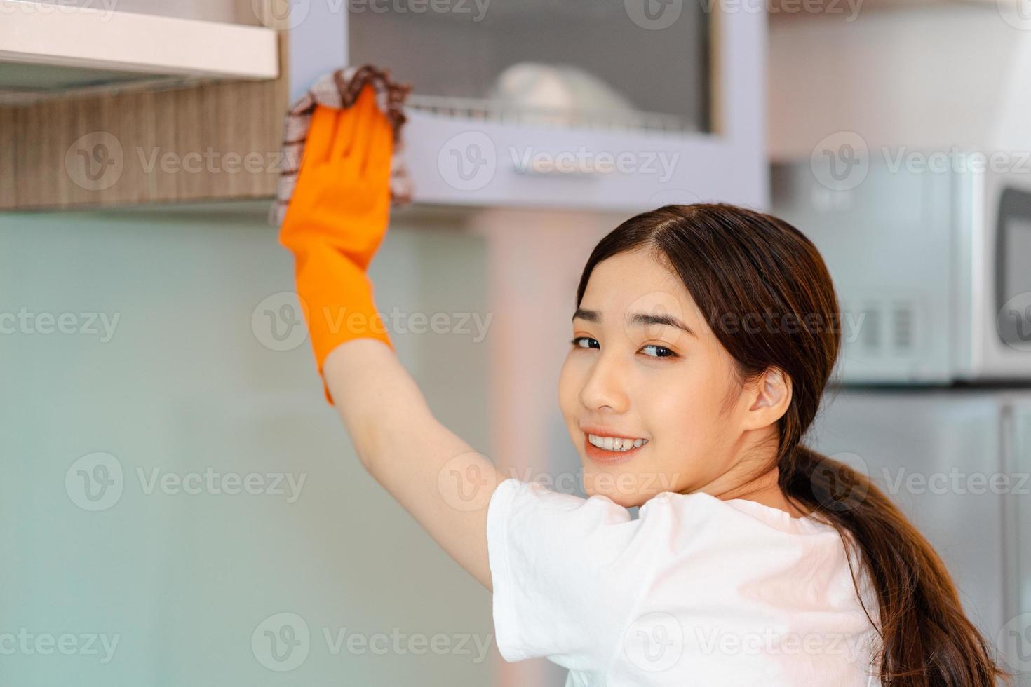 Hermosa mujer asiática limpiando gabinetes de cocina foto