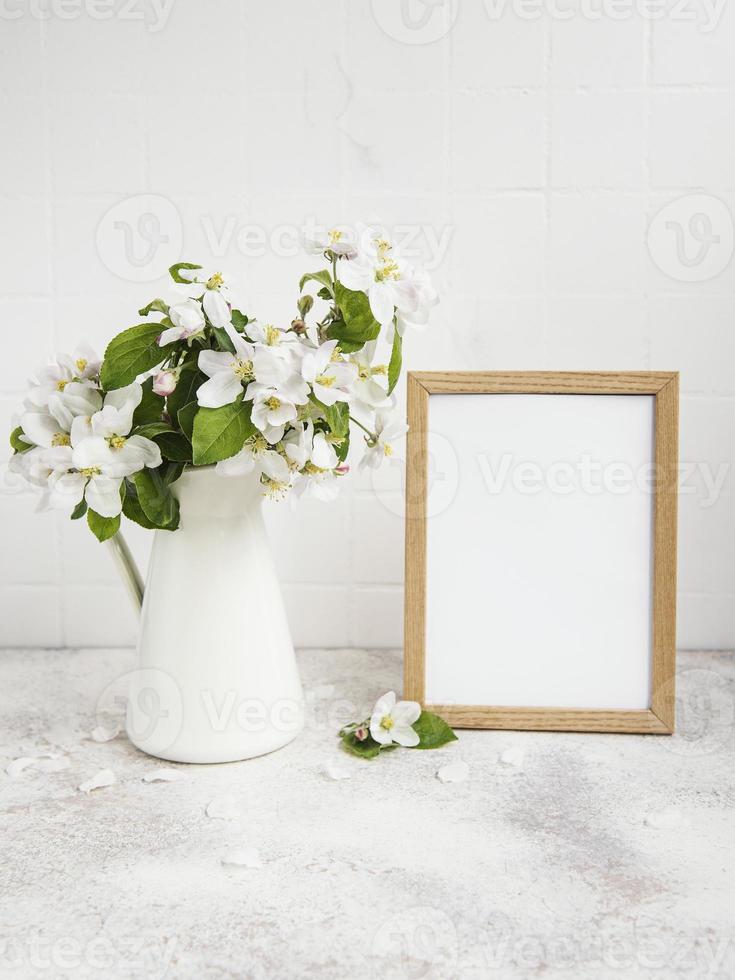 flor de manzana de primavera en un jarrón con un marco de fotos vacío