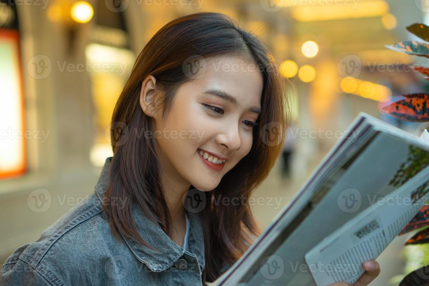 Beautiful Asian girl reading a magazine in the street photo