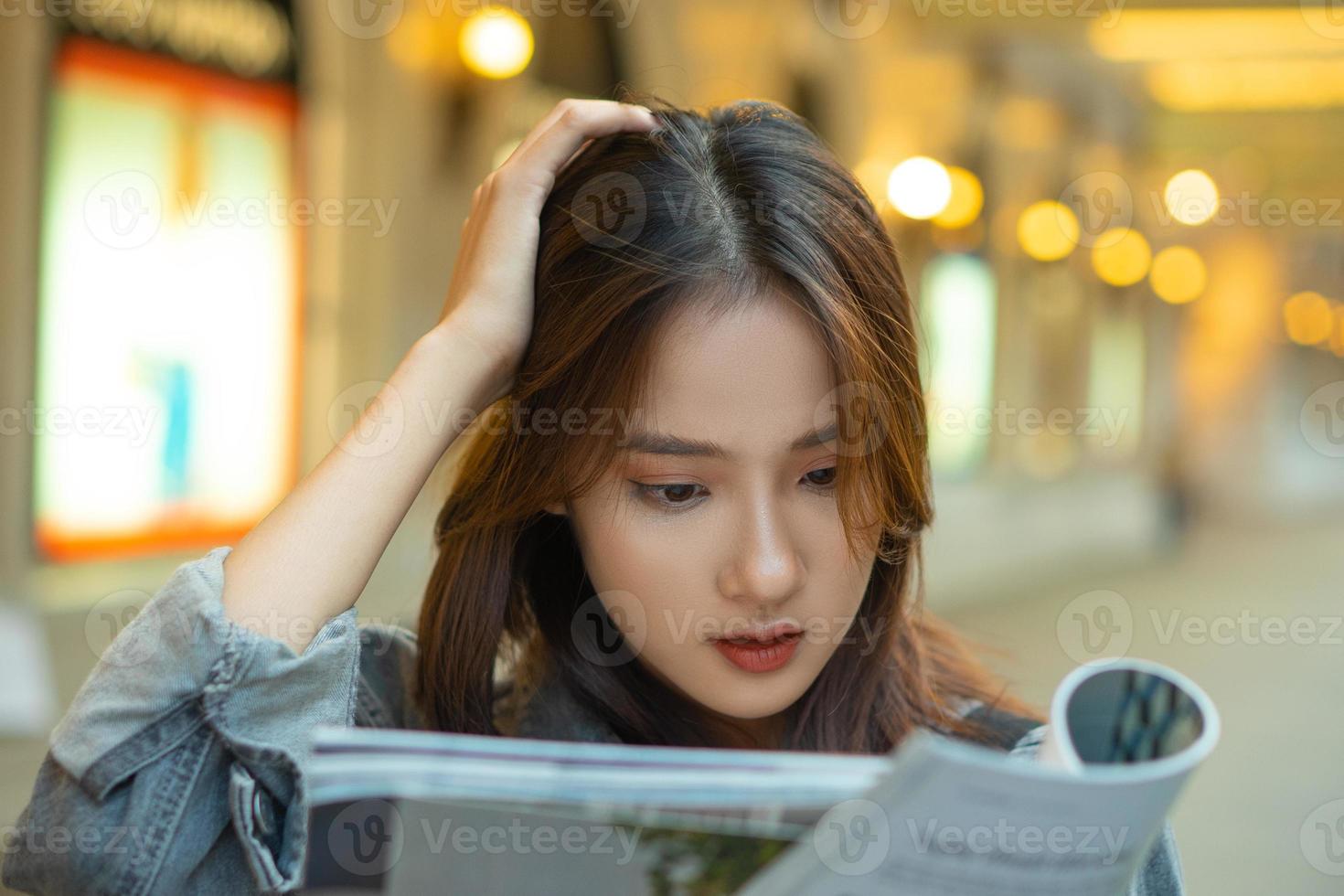 hermosa chica asiática leyendo una revista en la calle foto