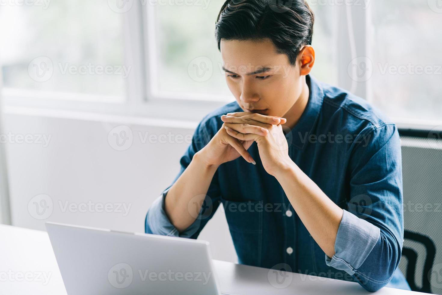 The Asian man was concentrating on his computer screen photo