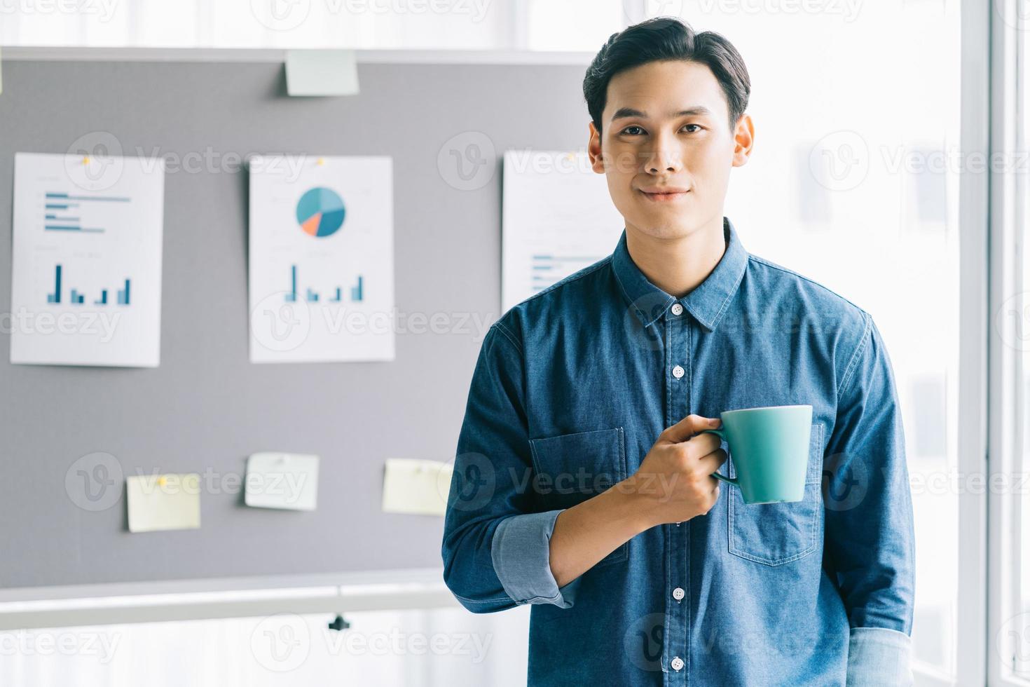 Asian man holding coffee cup standing smiling with planning board background photo