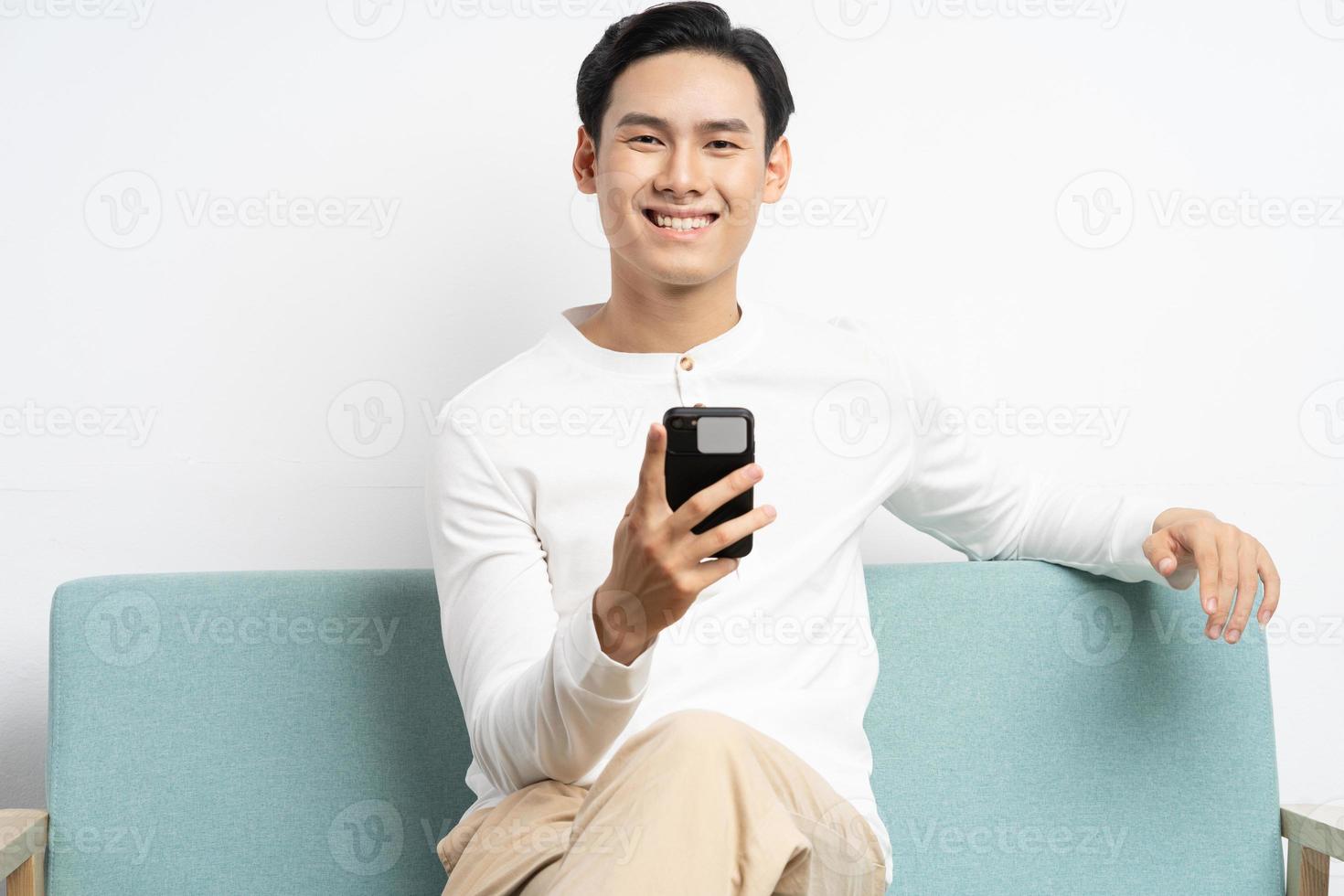 Asian businessman sitting on sofa and using phone photo