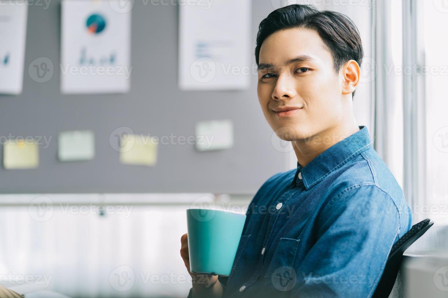 Hombre asiático sentado y bebiendo café durante el recreo foto