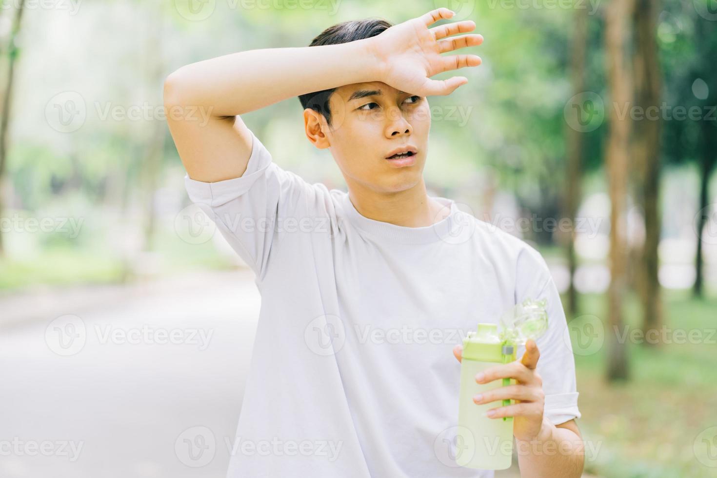 Asian man resting after jogging in park photo