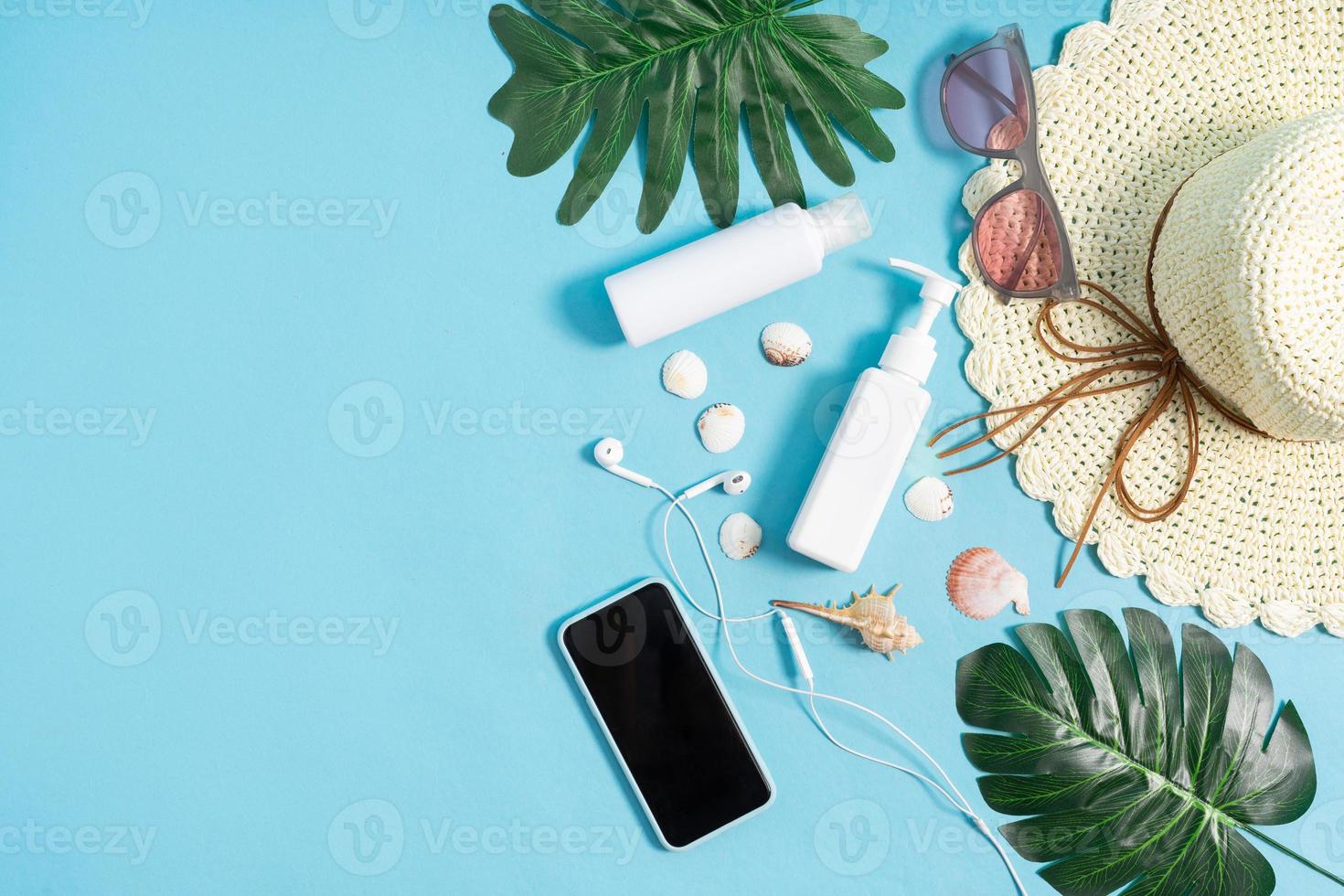 Two cosmetic jars displayed with seashells, phone and hat on a blue background photo