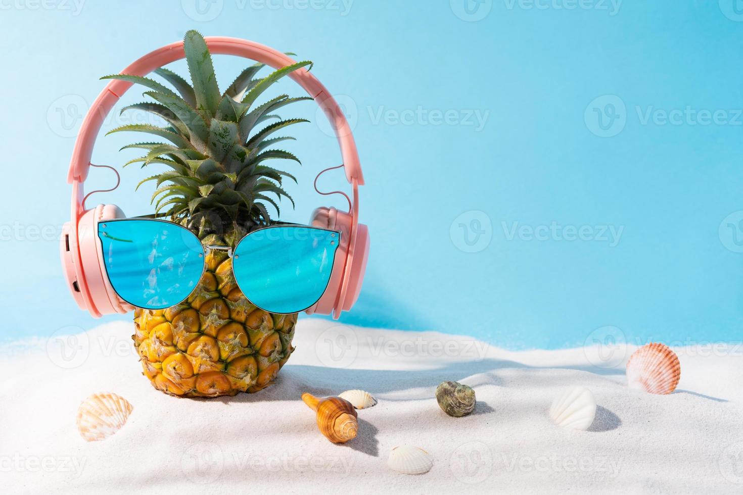 Pineapple wearing headphones and sunglasses on the sand photo