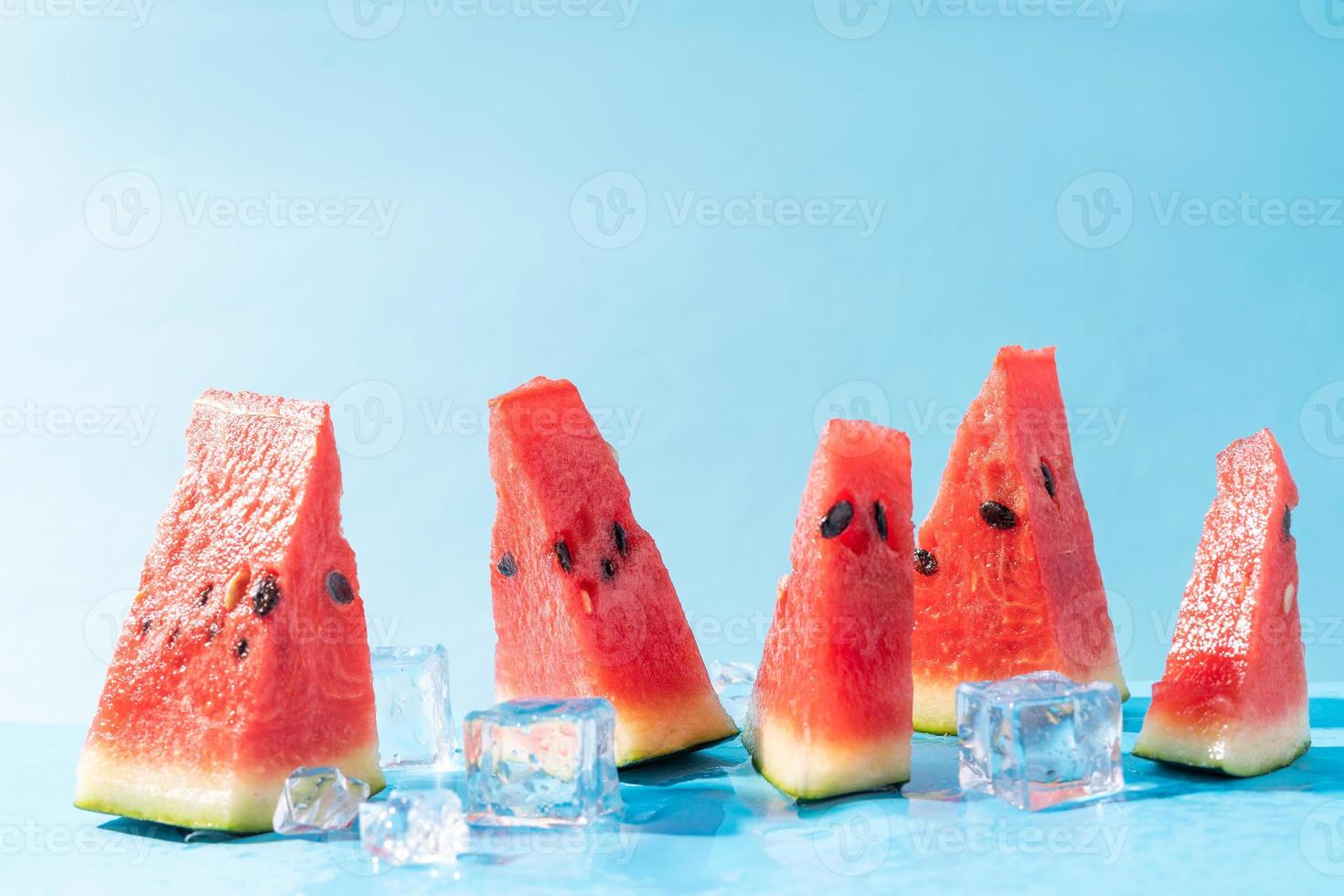 Rebanadas de sandía fresca con cubitos de hielo sobre un fondo azul. foto