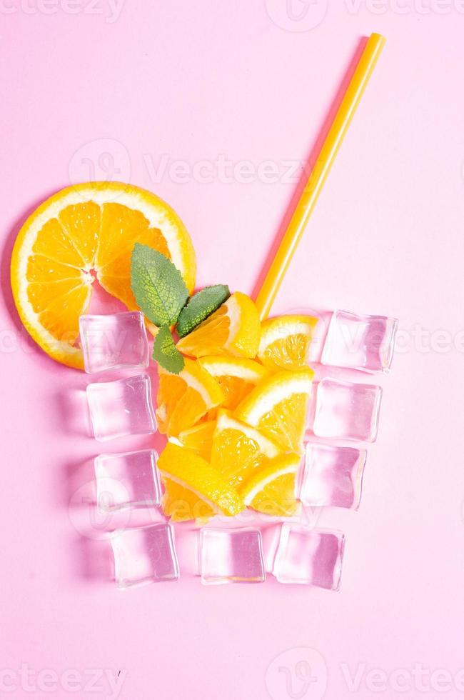 Orange juice cup made of ice cube on pink background photo