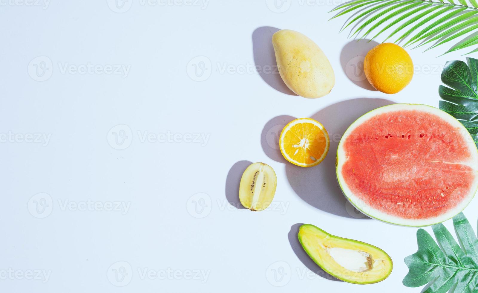 Tropical fruits like mango, orange, watermelon, avocado are arranged on a white background photo
