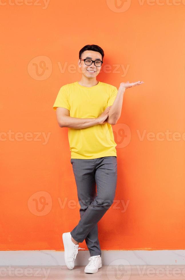 Full body photo of Asian man in yellow shirt on orange background