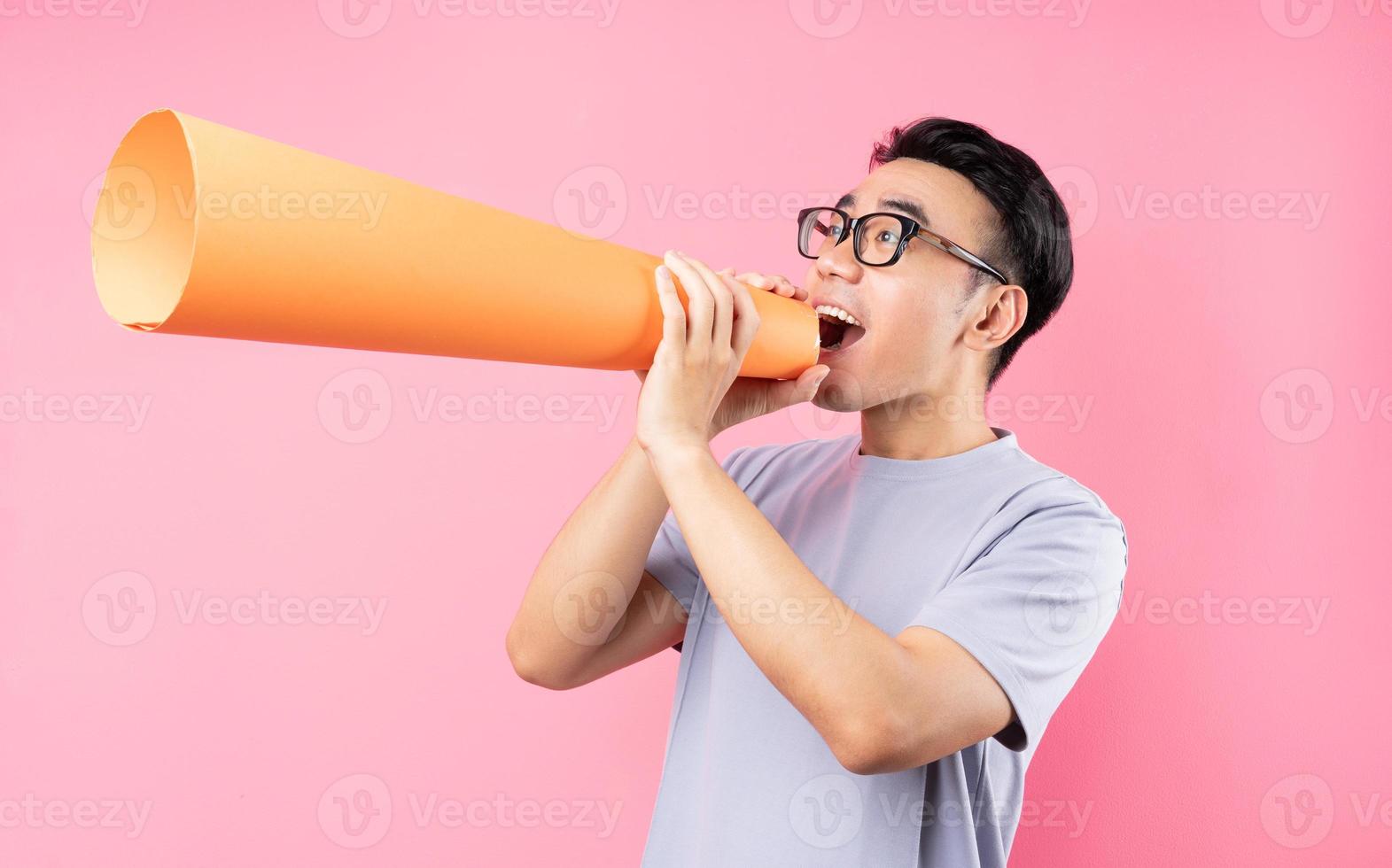 Asian man holding paper speaker on pink background photo