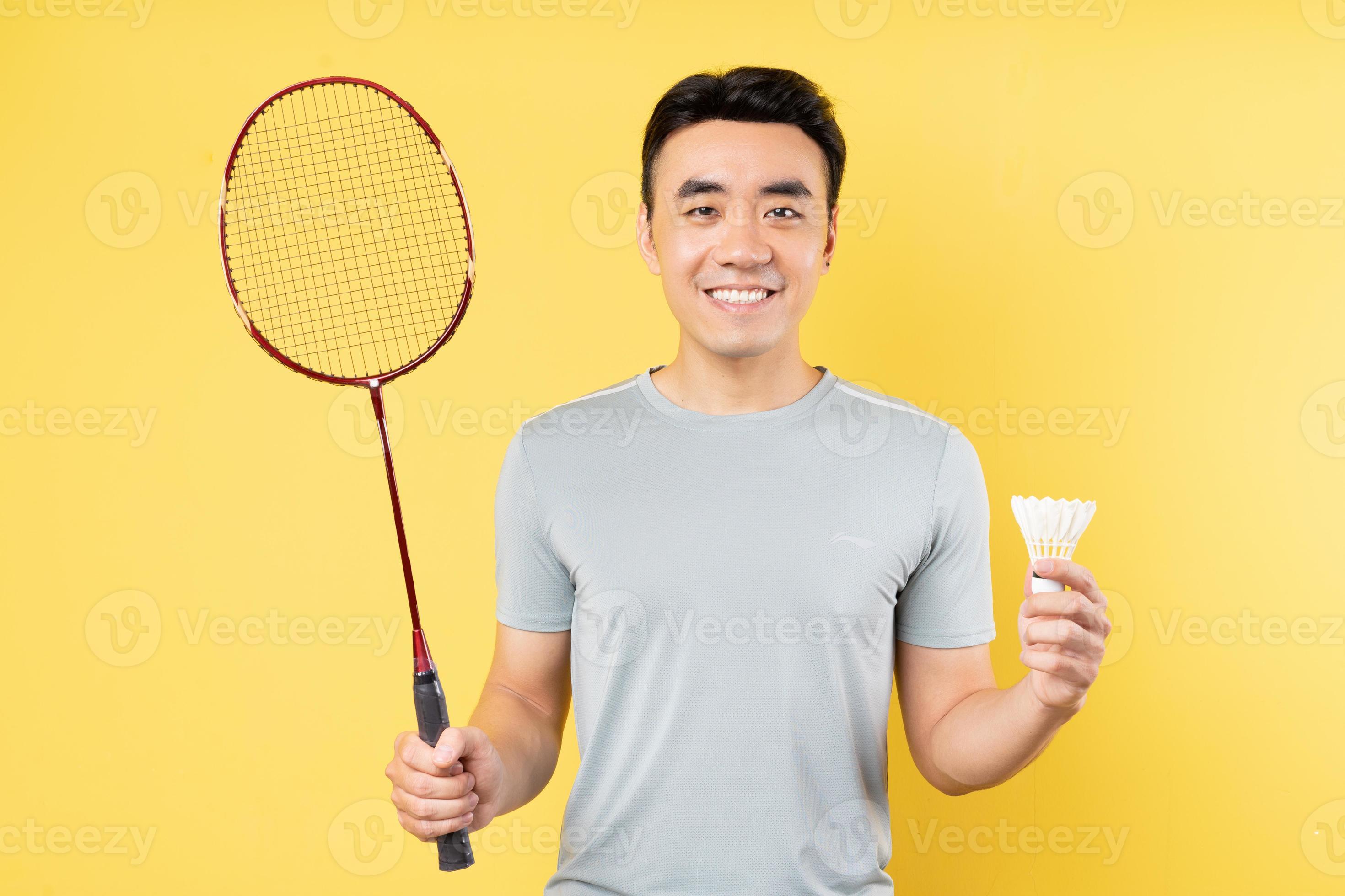 Portrait of an Asian man holding a badminton racket on a yellow