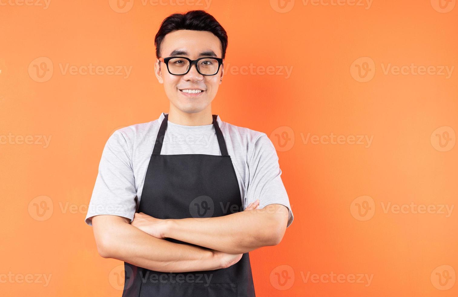 retrato, de, asiático, macho, camarero, posar, en, fondo naranja foto