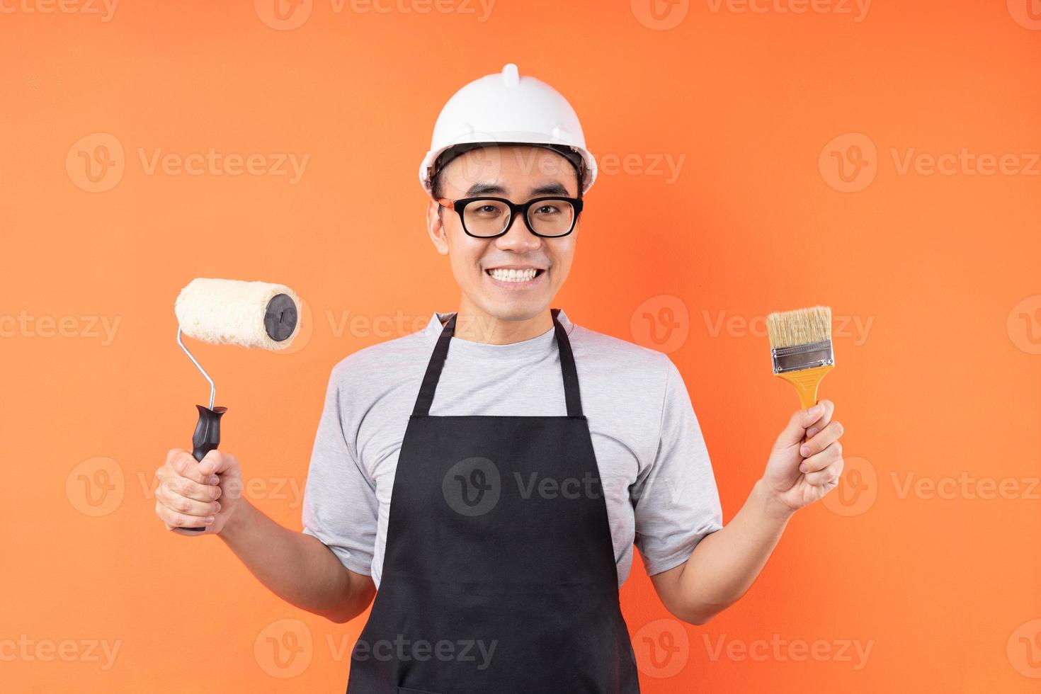 Pintor asiático sosteniendo pincel posando sobre fondo naranja foto