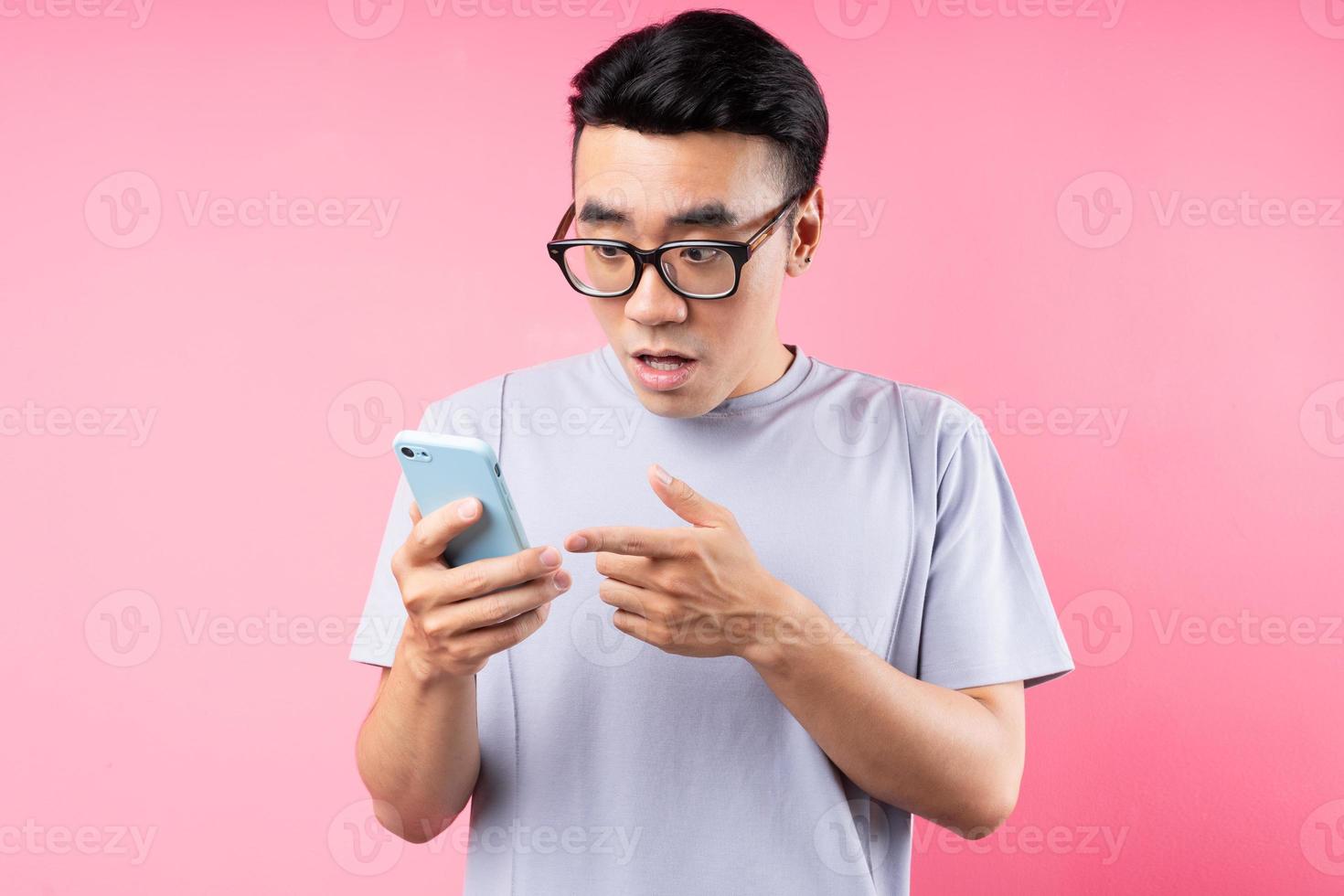 Portrait of Asian man using smartphone on pink background photo