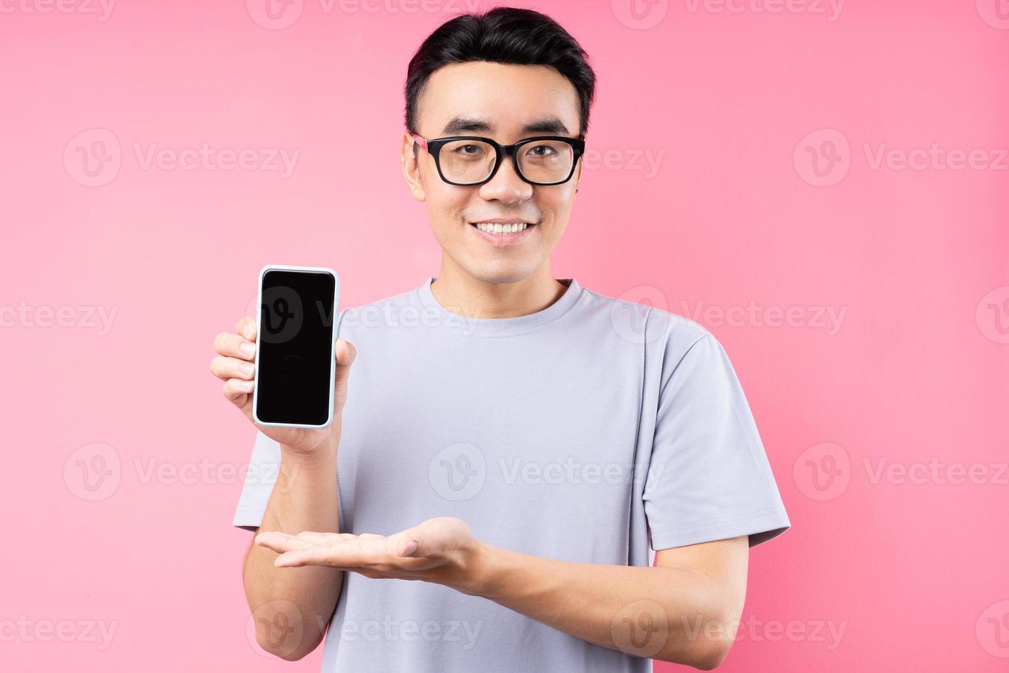 Retrato de hombre asiático con smartphone sobre fondo rosa foto