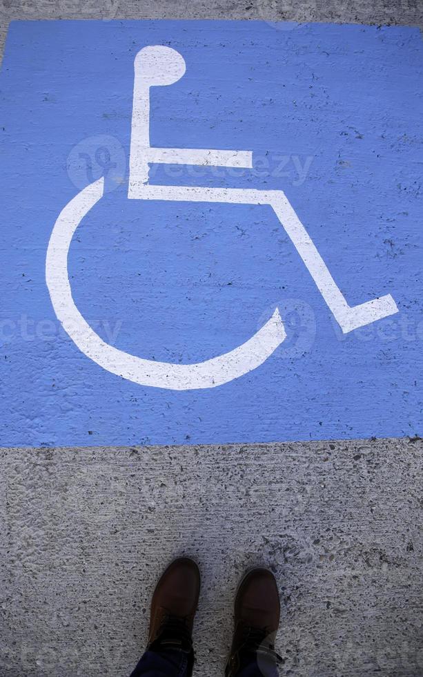 Pies en un cartel para discapacitados en el asfalto foto