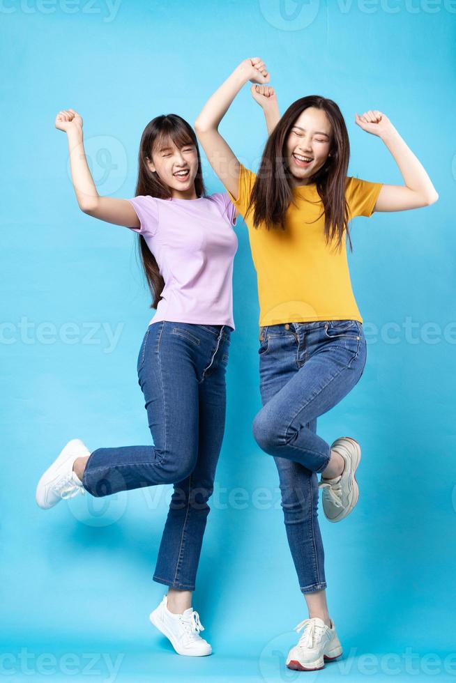 Full body portrait of two beautiful young Asian girls on a blue background photo