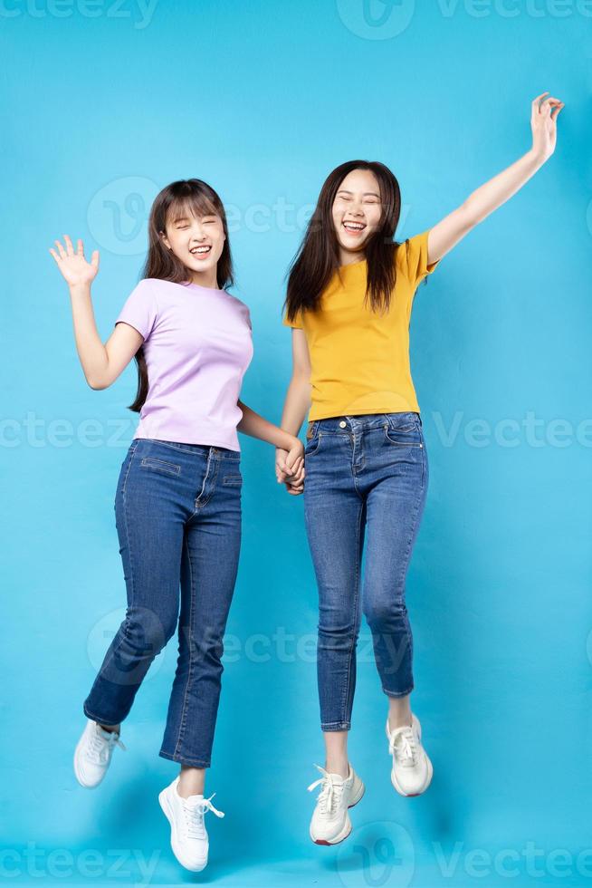 Full body portrait of two beautiful young Asian girls on a blue background photo