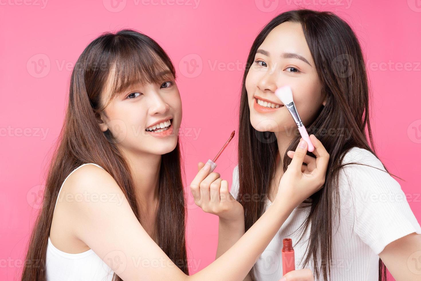 Two beautiful young Asian girls doing make up for each other photo